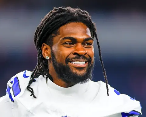 Celebration of Dallas Cowboys football player with dreadlocks and beard, smiling during game, wearing team jersey, in stadium atmosphere, showcasing team spirit and athletic success.