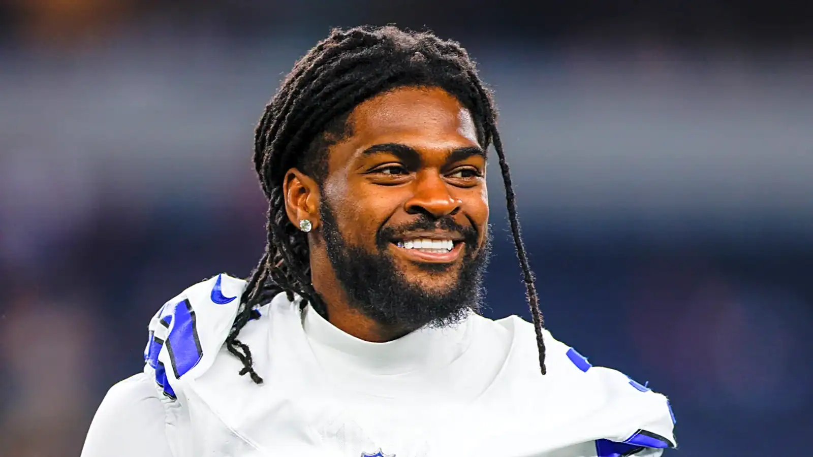 Celebration of Dallas Cowboys football player with dreadlocks and beard, smiling during game, wearing team jersey, in stadium atmosphere, showcasing team spirit and athletic success.