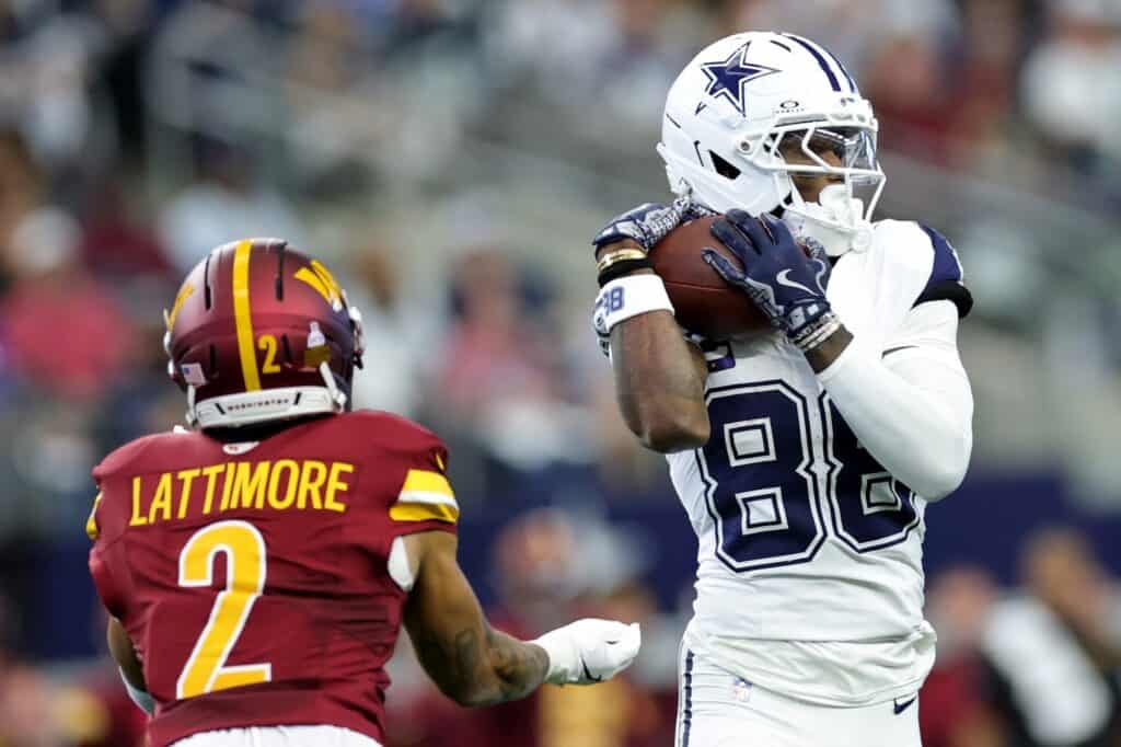 Amazing football action featuring Dallas Cowboys player catching a pass against Washington Commanders defender during a game, highlighting NFL football skills, team rivalry, and sports excitement.