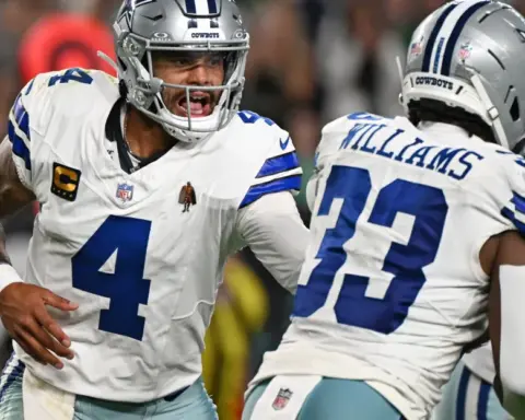 Dallas Cowboys quarterback Dak Prescott celebrating with teammates during a game, showcasing team spirit and leadership on the field.