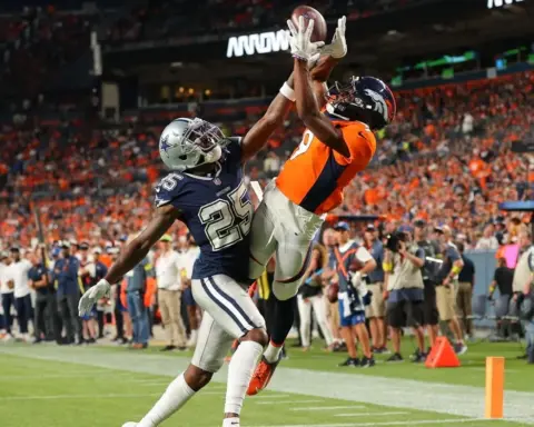 Athletic players competing for football reception in an NFL game, showcasing intense action and athleticism on the field.