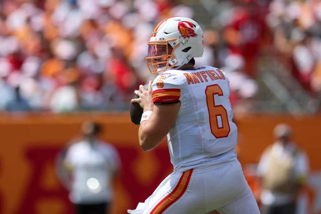 Quarterback Mayfield in action during an NFL game for the Kansas City Chiefs, wearing white jersey number 6 with team logo and helmet, preparing to throw a pass on the field.