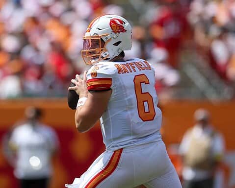 Quarterback Mayfield in action during an NFL game for the Kansas City Chiefs, wearing white jersey number 6 with team logo and helmet, preparing to throw a pass on the field.