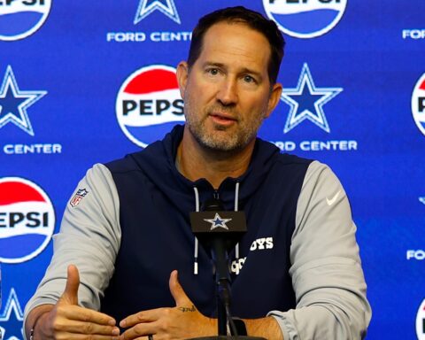 Dallas Cowboys head coach speaking at a press conference at Ford Center, with Pepsi and Cowboys branding in the background. Focus on NFL coaching staff, team updates, and inside the star sports coverage.