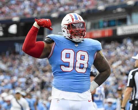 High-energy Dallas Cowboys player celebrating during an NFL game, wearing #98 jersey, blue and white uniform, with a crowd and referee in the background.