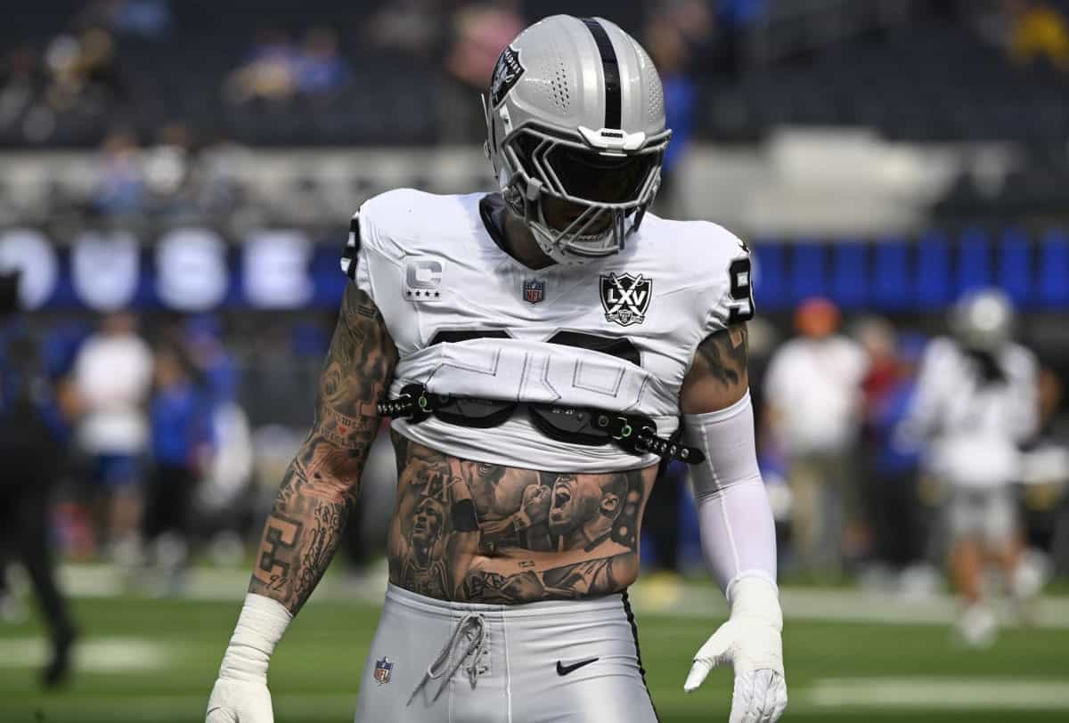 A professional football player wearing the Las Vegas Raiders uniform with tattoos on his torso and arms, celebrating during an NFL game on the field.