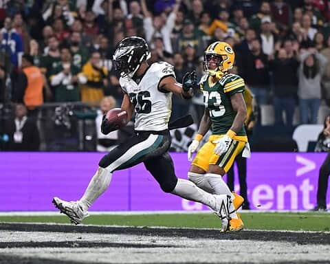 Running back with football in hand evading defenders during NFL game, Dallas Cowboys vs Green Bay Packers, inside the star football stadium.