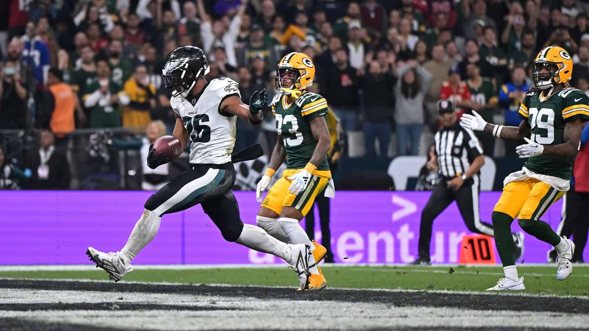 Running back with football in hand evading defenders during NFL game, Dallas Cowboys vs Green Bay Packers, inside the star football stadium.