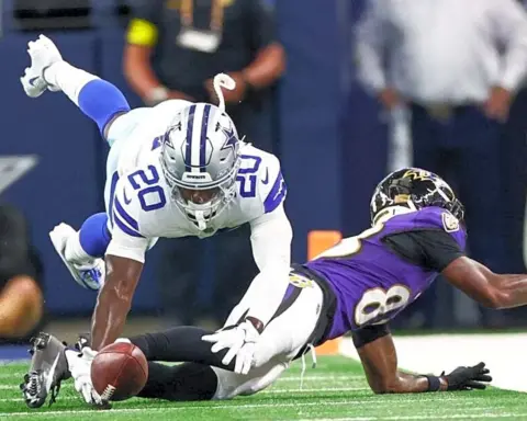 An intense moment in NFL action showing a Cowboys defender attempting to stop the Ravens receiver from crossing the goal line.