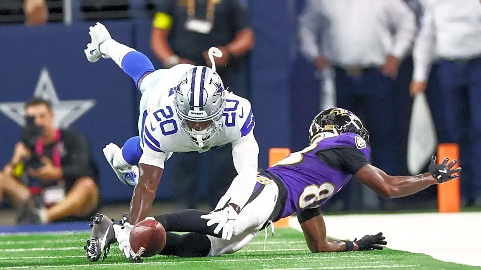 An intense moment in NFL action showing a Cowboys defender attempting to stop the Ravens receiver from crossing the goal line.