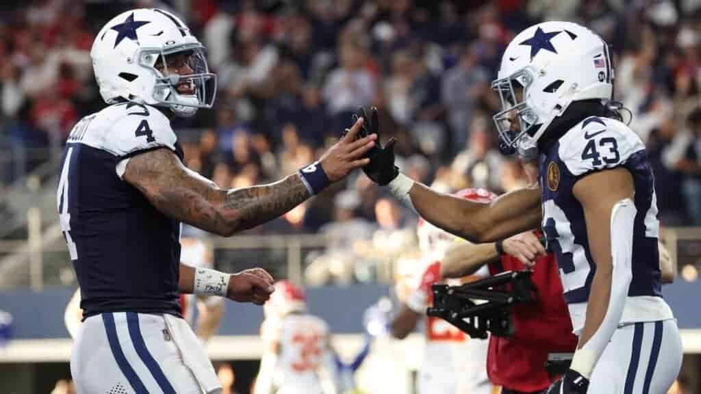 High-quality image of Dallas Cowboys players in football gear exchanging high-fives during a game, showcasing team spirit and on-field action.
