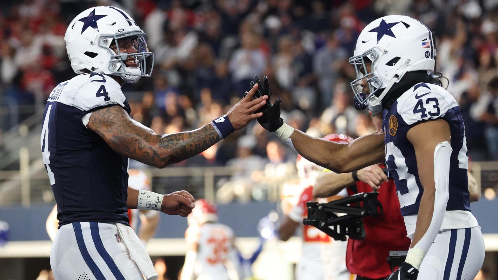 High-quality image of Dallas Cowboys players in football gear exchanging high-fives during a game, showcasing team spirit and on-field action.