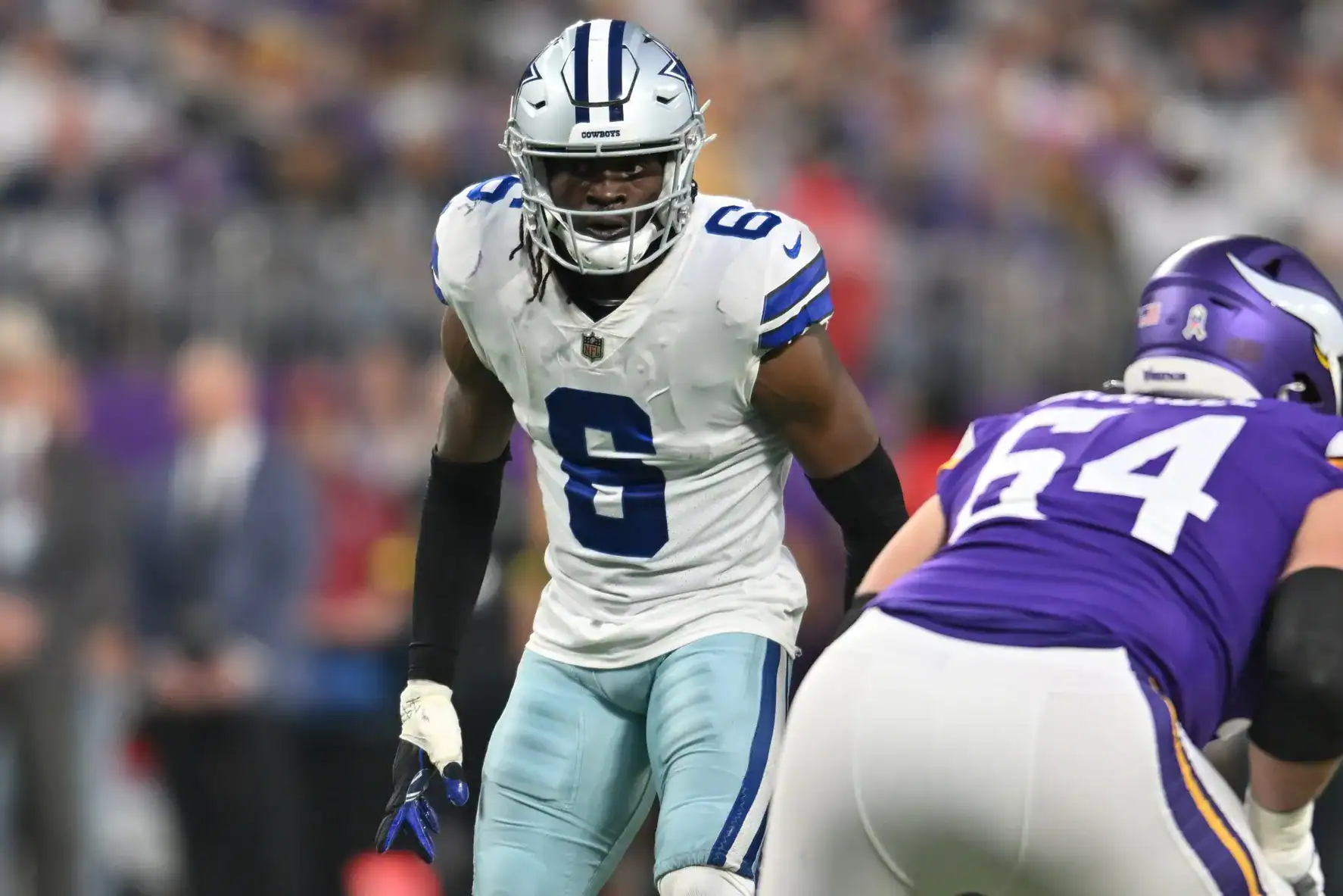 Dallas Cowboys football player in white jersey with blue accents, during an NFL game against Minnesota Vikings, close-up action shot, intense moment on the field, American football game.