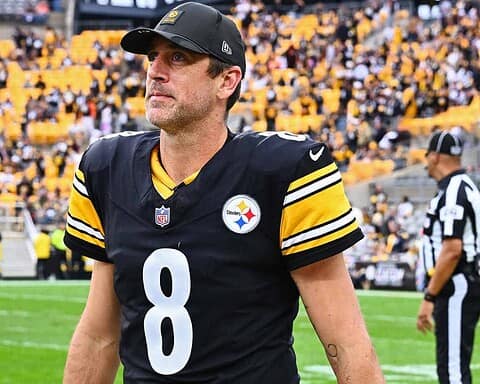 Close-up of Tom Brady in a Steelers uniform on the football field, highlighting his focused expression amidst the crowd, emphasizing sports passion and NFL action.