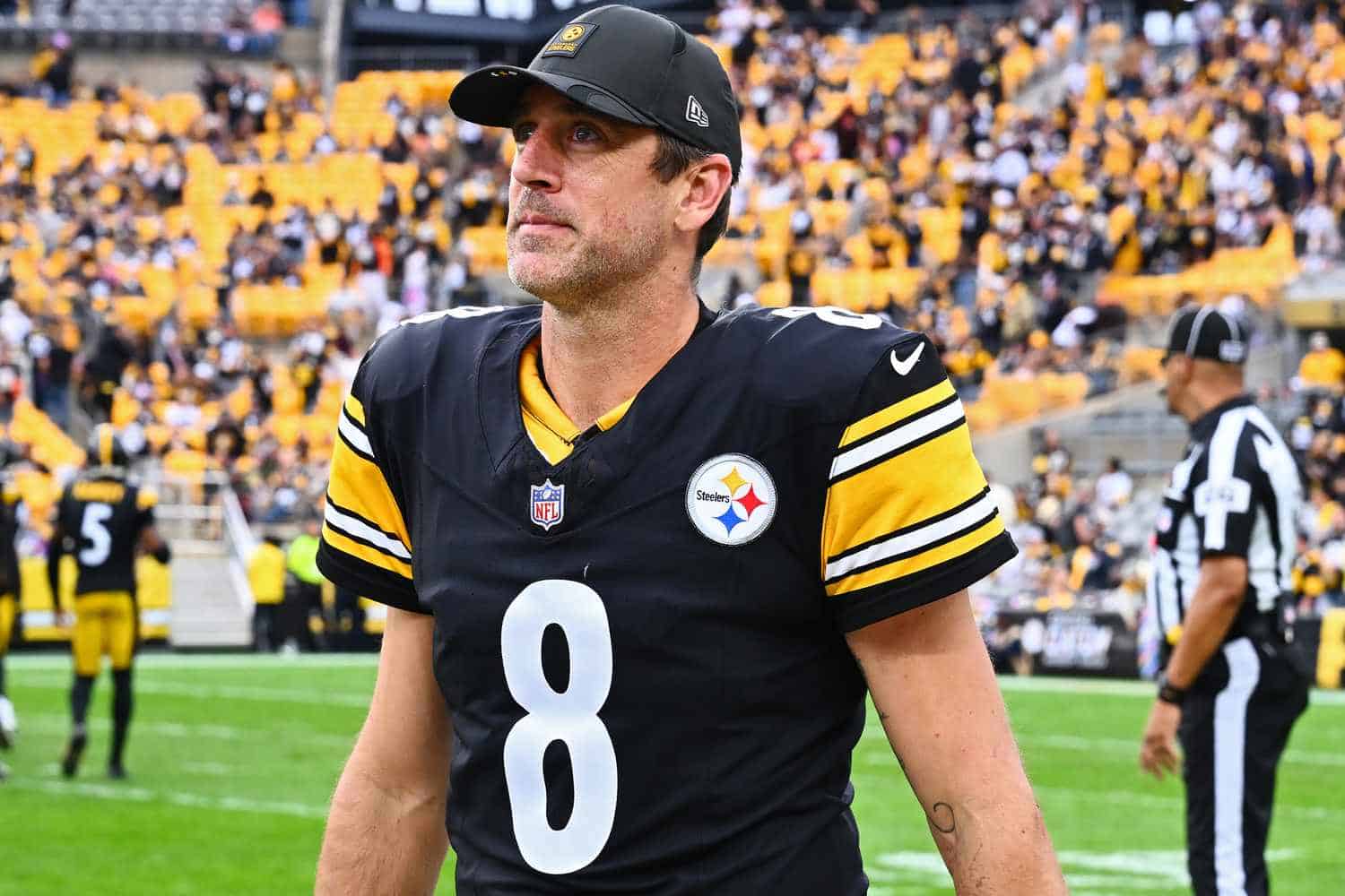 Close-up of Tom Brady in a Steelers uniform on the football field, highlighting his focused expression amidst the crowd, emphasizing sports passion and NFL action.