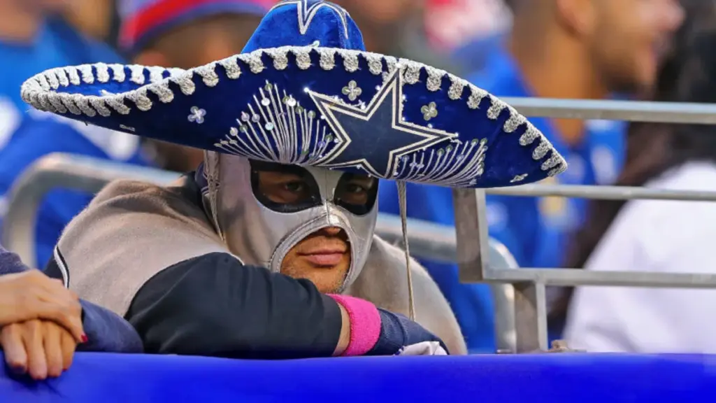 Fan wearing a Dallas Cowboys sombrero and mask at a sports game, showing team spirit and enthusiasm for Dallas Cowboys football games, capturing the vibrant fan culture and game-day excitement.