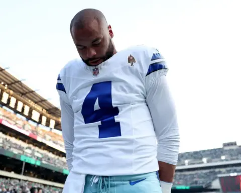 A football player in a Dallas Cowboys uniform with the number 4, standing on the field after a game at AT&T Stadium, showcasing team pride and sportsmanship.