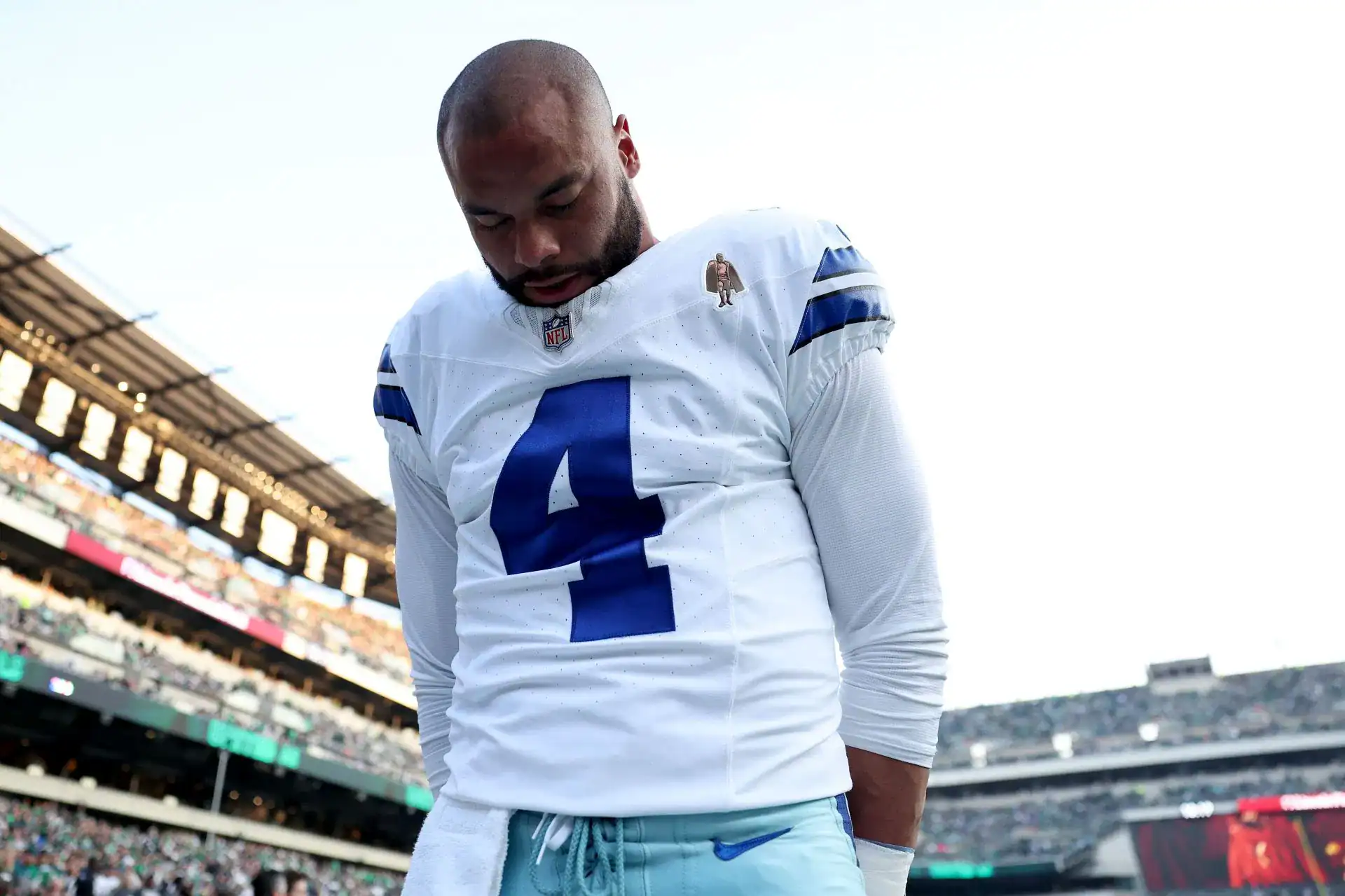 A football player in a Dallas Cowboys uniform with the number 4, standing on the field after a game at AT&T Stadium, showcasing team pride and sportsmanship.