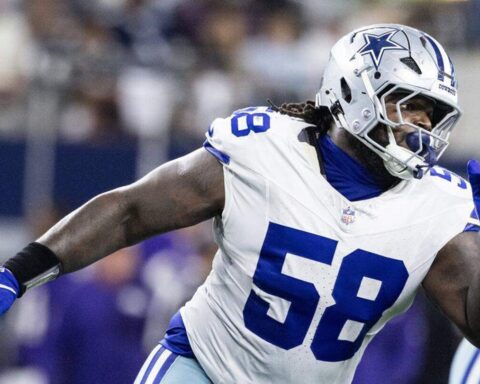 Dallas Cowboys linebacker in game action, wearing white jersey number 58, with a helmet featuring Cowboys star logo, on the football field during an NFL game.