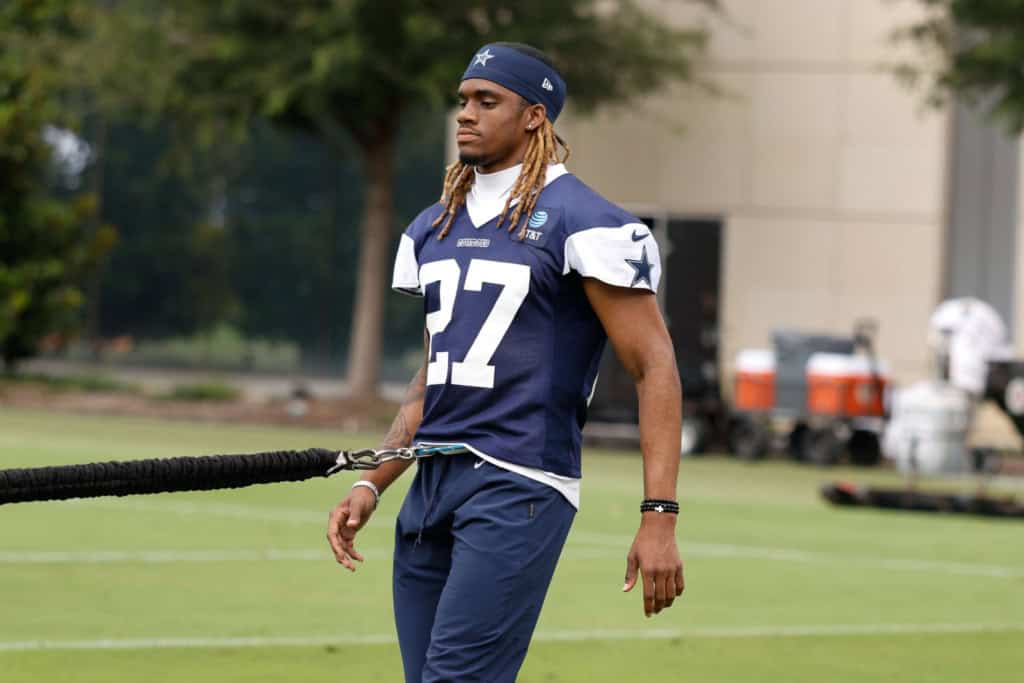 Dallas Cowboys football player during practice, wearing jersey number 27, on the field with training equipment in the background.